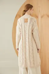 Saco largo tejido en flama color beige, con punto trenzado y desagujado. Lleva botones grabados y detalle de cuero.