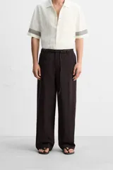 Pantalón relaxed fit color marrón oscuro confeccionado en tejido con mezcla de algodón y lino. Cintura elástica, bolsillos laterales y bolsillo trasero de plastrón. Perneras con pliegues frontales. Cierre en delantero con cremallera y botón.