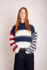 Sweater de punto suave con efecto peluche, diseño a rayas horizontales en blanco, azul y rojo. Corte recto y cuello redondo.
