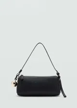 Bolso negro tipo baguette con correa de hombro fina y charm dorado en forma de esfera.