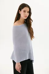 Poncho color beige de tejido de punto con cuello asimétrico.