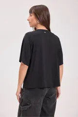 Remera negra de corte recto con cuello redondo y bolsillo en el pecho. Detalles de tachas plateadas en cuello, mangas y bolsillo.