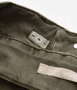 Pantalón flare color verde militar confeccionado en sarga con elastano, tiro alto, cintura ancha con trabillas, doble botón, cierre por cremallera, bolsillos y detalle de recortes.