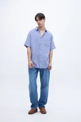 Camisa celeste de manga corta con cuello solapa clásico, bolsillo en el pecho y botones personalizados.