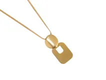 Collar de acero con baño de oro, compuesto por una cadena tipo serpiente y un dije colgante de dos piezas: una ovalada y una rectangular con un recorte central.