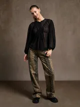 Blusa color crema con cuello redondo, botones frontales y mangas largas abullonadas.