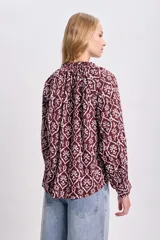 Blusa de manga larga color bordó con estampado floral en blanco, cuello redondo con lazo ajustable y corte holgado.