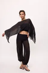 Pantalón negro traslúcido con corte ancho y ajuste en los tobillos.