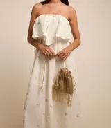 Vestido midi evasé sin mangas, confeccionado en tricolina color blanco, con escote recto con volantes y bordados metalizados de iconos.