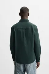 Camisa azul marino de corte regular fit, confeccionada en tejido de algodón Oxford. Tiene cuello abotonado, manga larga con puños abotonados, bolsillo de parche en el pecho y cierre frontal con botones.