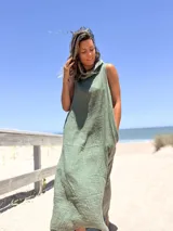 Vestido largo verde oliva de lino, con cuello caído, sin mangas y bolsillos laterales.