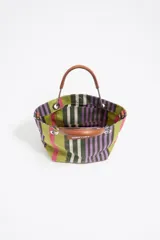 Bolso de mano mini de la marca Bimba y Lola con diseño de rayas verticales en tonos verde, violeta, rosado y blanco. Presenta estructura rígida, asas de mano de piel marrón con herrajes metálicos y una correa larga regulable. Incluye etiqueta frontal con el logo de la marca y cierre magnético.