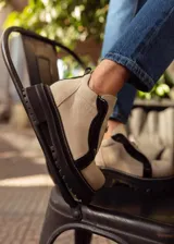 Botines de cuero negro con paneles laterales de charol, cierre frontal con cremallera y suela track.