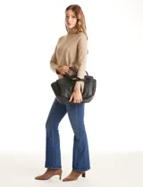 Cartera tote negra de ecocuero con base redondeada y pliegues decorativos. Cuenta con una solapa central con herraje dorado en forma de "T" y asas dobles para hombro y mano. El interior tiene triple compartimento.