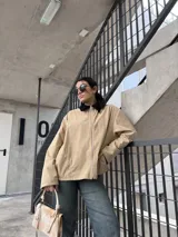 Campera de pana color beige con cierre frontal y cuello negro.