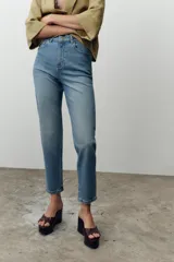 Jeans de tiro alto color celeste, corte mom fit, con cinco bolsillos y cierre frontal con cremallera y botón.
