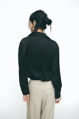 Camisa marrón satinada de cuello solapa, escote pico, manga larga y cierre frontal con botones.