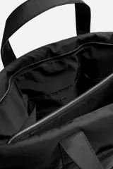 Bolso tipo shopper negro fabricado en tejido técnico. Cuenta con un compartimento principal con cierre de cremallera y un bolsillo interior con cierre. En la parte frontal tiene tres bolsillos. Tiene dos asas de mano.