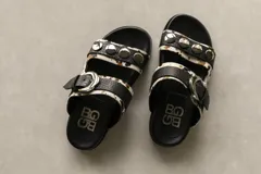 Sandalias bajas con dos tiras, una con hebilla y otra con apliques metálicos.
