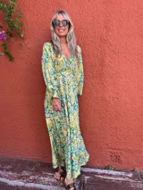 Vestido largo de seda con escote en V y mangas largas amplias. Presenta un estampado tipo cachemir o mandala en tonos verde, amarillo y blanco/crudo.