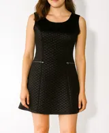 Vestido corto negro con textura matelasseada, corte al cuerpo, sin mangas y cierre con cremalleras plateadas a la altura de la cadera.