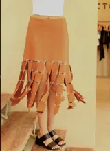 Falda midi color terracota, de cuero genuino, con tiras colgantes decorativas unidas por argollas metálicas.