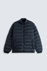Cazadora acolchada azul marino de tejido técnico, cuello subido, manga larga, bolsillos de vivo en la cadera, acabados elásticos y cierre frontal de cremallera.