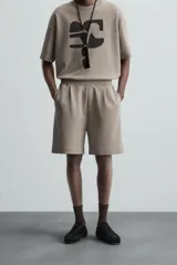 Bermuda color arena de tejido interlock de algodón con elasticidad, corte relaxed fit, cintura elástica ajustable con cordón interior, bolsillos laterales y bolsillo trasero de plastrón.