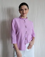 Camisa lila con cuello mao con volados, abotonada al frente con botones marrones, mangas 3/4 con detalle de costuras en los hombros.