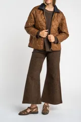 Campera capitoneada de color marrón con diseño de flores pespunteadas, cuello camisero en contraste oscuro y cierre frontal de cremallera.