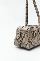 Cartera baguette color marrón claro, confeccionada en símil cuero con formato cilíndrico y doble asa corta.