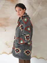 Saco de lana marrón con diseño geométrico multicolor, cuello con solapa, cierre frontal con botones y bolsillos delanteros.