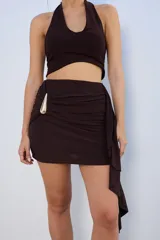 Minifalda marrón con drapeado lateral y detalle de hebilla dorada.