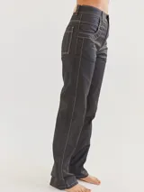Pantalón jean recto color negro con costuras blancas contrastantes.