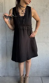 Vestido corto negro con escote en V, breteles finos y detalle de encaje en el busto.