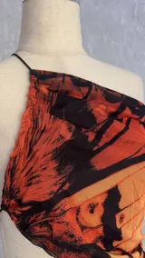 Minivestido con estampado de mariposas en tonos naranja y negro, con escote halter asimétrico y abertura en la cintura.