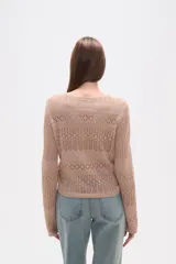 Sweater de poliéster color beige, con cuello en V, manga larga y frunces ajustables en el frente. Presenta un diseño de tejido calado.