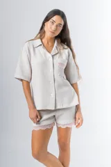 Conjunto de pijama de tela waffle color crema, compuesto por una camisa de manga corta con botones, bolsillo y detalle de broderie, y un short con elástico y cordón en la cintura con terminación de broderie.