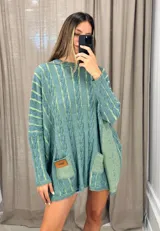 Sweater tejido de punto color fucsia con diseño de trenzas verticales en color naranja. Tiene cuello redondo y dos bolsillos frontales.