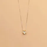 Conjunto de collar y aros con dije circular de plata y borde de oro con circonia engarzada.