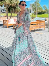 Vestido largo de polysilk con estampado paisley en tonos azul, celeste y dorado. Tiene escote en V, mangas largas acampanadas y corte amplio.