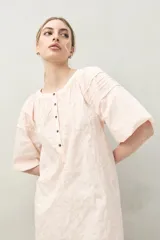 Vestido corto blanco de algodón con bordado floral en relieve, escote redondo con abotonadura frontal y mangas amplias.