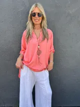 Blusa color salmón de viscosa, corte clásico, con cuello mao y mangas largas con puños abotonados.