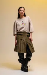 Remera oversize de algodón premium color beige, con cuello redondo y manga corta. Presenta un estampado central de Mickey Mouse en una pose dinámica.