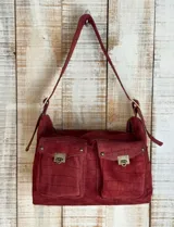 Bolso bandolera color borgoña con textura símil piel de cocodrilo, con correa fina ajustable y dos bolsillos frontales con cierre de broche metálico.