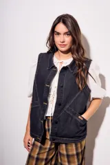 Chaleco oversize de denim negro con costuras en hilo ocre, cuello camisero, cierre frontal con botones y bolsillos delanteros.