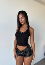 Musculosa negra de tejido acanalado con cuello halter adornado con ojales metálicos.