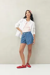 Short pollera de denim azul con corte asimétrico y cierre con botón.