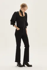 Jean negro de tiro medio con silueta levemente acampanada desde la rodilla.