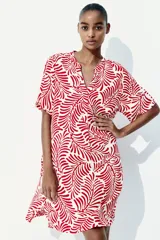 Vestido túnica a la rodilla en tejido liviano de viscosa con cuello mao y abertura en V. Modelo de corte holgado con hombros levemente caídos, mangas cortas y bajo recto con tajos laterales. Parte posterior algo más larga. Sin forrar. Estampado con motivos de hojas rojas.